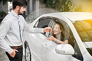 Car dealership. The woman receiving car key with a smile from the salesman. Auto Leasing Business