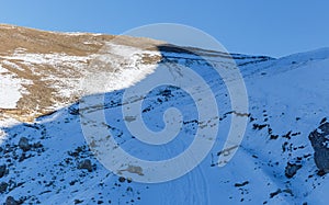 A car descends on a snow-covered road in the mountains