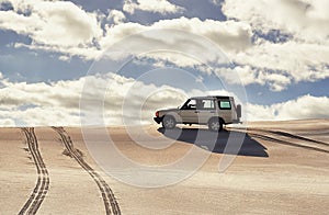 Car, desert and driving with travel and transport outdoor, off road vehicle for sand dunes and journey on vacation. Van