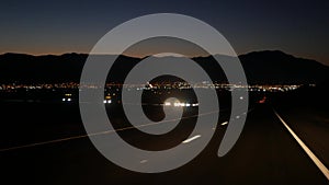 Car on desert valley road at night, highway in twilight dusk. Road trip in USA.