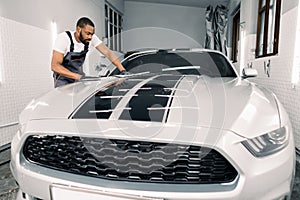 Auto detailování a čistenie. samec auto umyť pracovník nosenie šedá kombinéza a rukavice obrúsky 