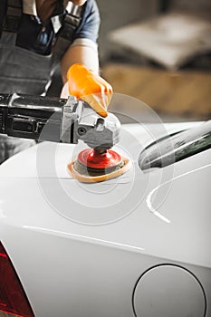 Car detailing. Close up of man with orbital polisher in auto repair shop. photo