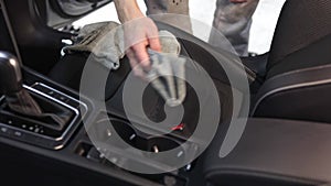 Car detailing concept, young man cleaning vehicle seats with a rag and a brush in car studio, car care