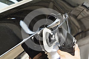 Car detailing - Hands with orbital polisher in auto repair shop. Selective focus.