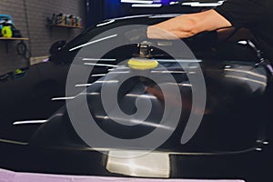 Car detailing - Hands with orbital polisher in auto repair shop. Selective focus.