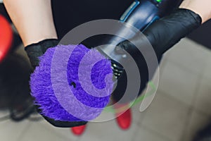 Car detailing - Hands with orbital polisher in auto repair shop. Selective focus.