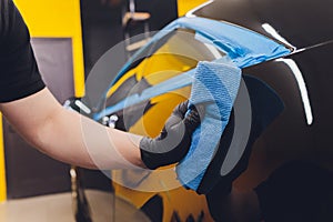 Car detailing - Hands with orbital polisher in auto repair shop. Selective focus.