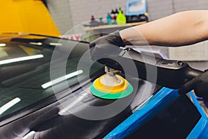 Car detailing - Hands with orbital polisher in auto repair shop. Selective focus.