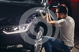 Car detailing - man with orbital polisher in auto repair shop. Selective focus. photo