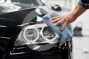 Car detailing - the man holds the microfiber in hand and polishes the car