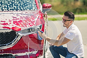 Car detailing - the man holds the microfiber in hand and polishes the car. Man worker washing car`s alloy wheels on a car wash.