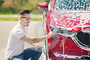 Car detailing - the man holds the microfiber in hand and polishes the car. Man worker washing car`s alloy wheels on a car wash.