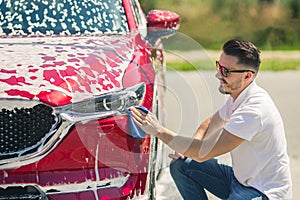 Car detailing - the man holds the microfiber in hand and polishes the car. Man worker washing car`s alloy wheels on a car wash.