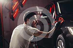 Auto detailování muž mikrovlákno v ruke a leštidla auto 