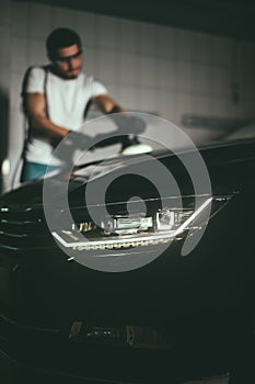 Car detailing - man with orbital polisher in auto repair shop. Selective focus.