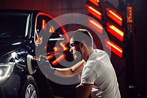 Car detailing - man with orbital polisher in auto repair shop. Selective focus.