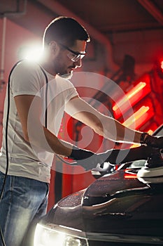 Car detailing - man with orbital polisher in auto repair shop. Selective focus.