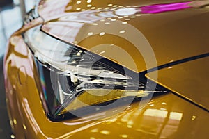 Car detailing series: Clean headlights of yellow sports car.