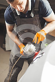 Car detailing series: polishing white vehicle in auto repair shop.