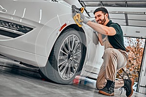 Car detailing series. Worker cleaning white car