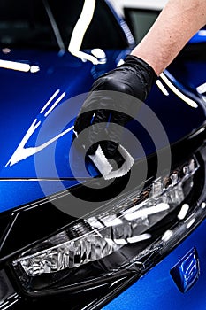 Car detailing studio or car wash worker applying ceramic car coating on blue car