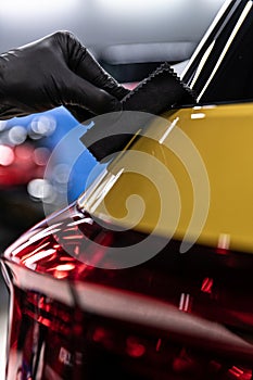 Car detailing studio worker applying ceramic coating on car
