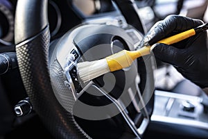 Car detailing. Vacuuming and cleaning of nooks on the dashboard and at the car steering wheel