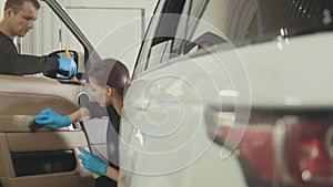 Car detailing - woman is cleaning dashboard in luxury vehicle