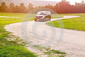 Car on dirt road curve and green grass park