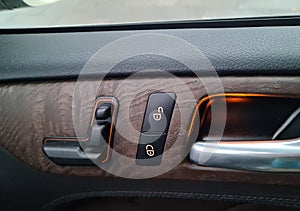 Car door lock switch inside luxury car interior with leather and wood design