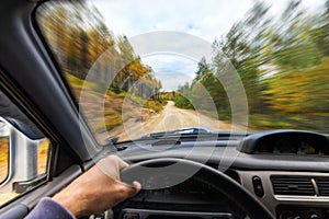 Car drive trough autumn forest by a dirt road