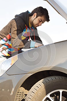 Car driver examining the car's engine