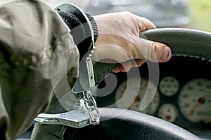 Car driver hand handcuffed to steering wheel, arrest, driving ban