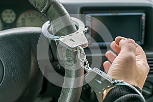 Car driver hand handcuffed to steering wheel, arrest, driving ban by traffic violator