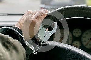 Car driver`s hand handcuffed to steering wheel photo