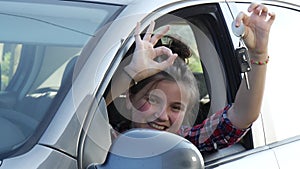 Car driver teenage girl happy showing car keys out window