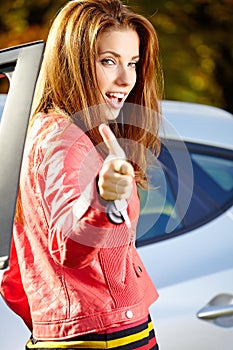 Car driver woman showing new car keys and car.