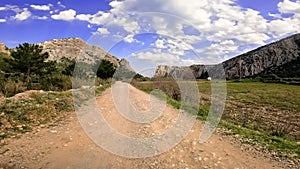 A car drives on a dirt road, driving through mountains under a clear sky, POV. Featuring dirt road, driving in scenic