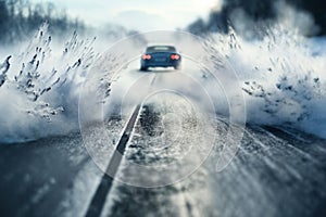 a car drives fast on a winter slippery road creating a whirlwind of snow, the concept of safety on a slippery road