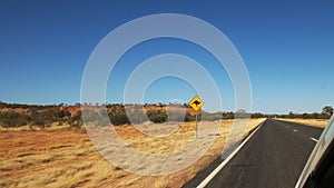 Car drives past a kangaroo road sign in outback Australia