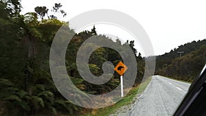 Car drives past a kiwi road sign in nz