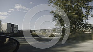 Car drives past lot of trucks on highway. Stock footage. View from window of moving car on village road. Trip by car on