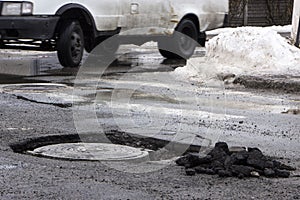 The car drives past the pothole with puddles on the road