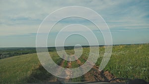 The car is driving along a country road nature .man driving a car on nature view from the window hills summer greens