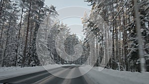 Car driving along the forest road in winter. Driving POV on snowy country road. Snow covered road