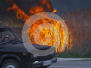 Car is driving along the road near the fire