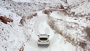 The car is driving along a snow-covered mountain road along the Konorchek Canyon. Rear view.