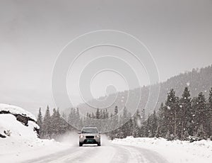 Car driving along snow covered road in a snowstorm