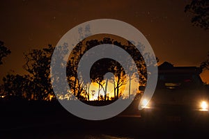 car driving away from a bushfire, forest is really bright because of the fire, litchfield national park, australia