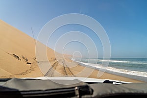 Car driving at dirt road in desert. Sand drive at the beach. Coast of sea.